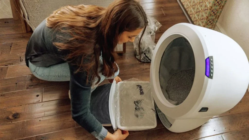 Litter-Robot 4 Review (2026): Is It Worth It or Overhyped? 6 person emptying Litter-Robot 4 waste drawer showing maintenance and cleaning process of automatic litter box